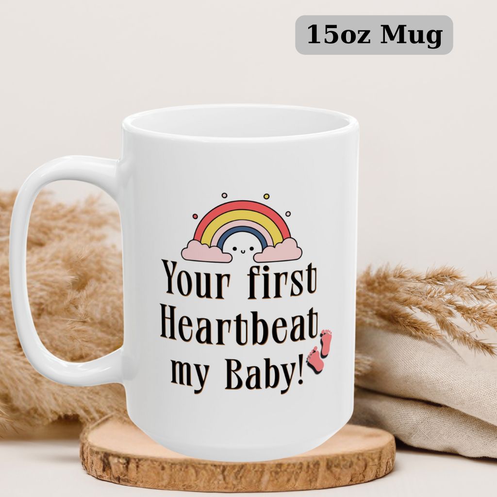 Mug mockup with the phrase "Your first heartbeat, my baby!" and a rainbow, ideal for gifting to new moms or dads. 15oz Mug.