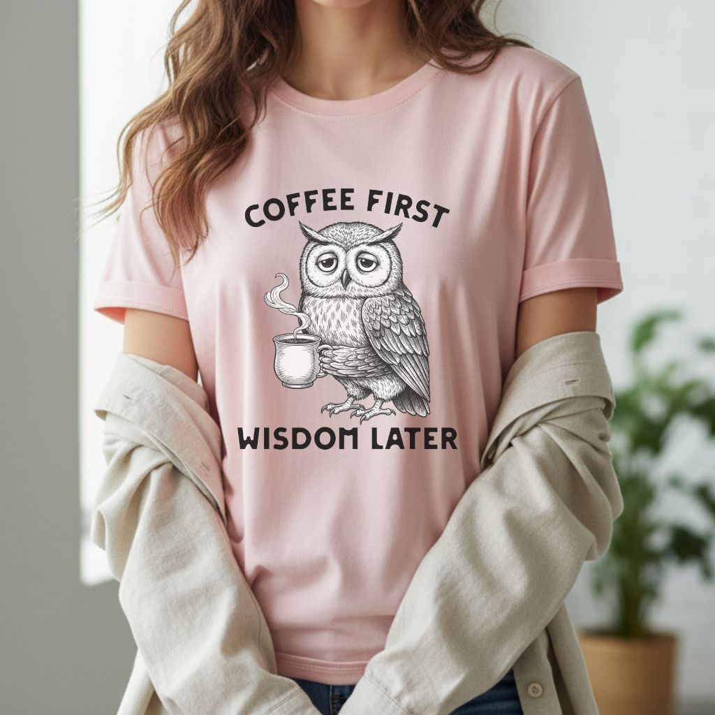 Soft pink women’s t-shirt with owl coffee graphic and Coffee First Wisdom Later phrase, feminine and casual style.